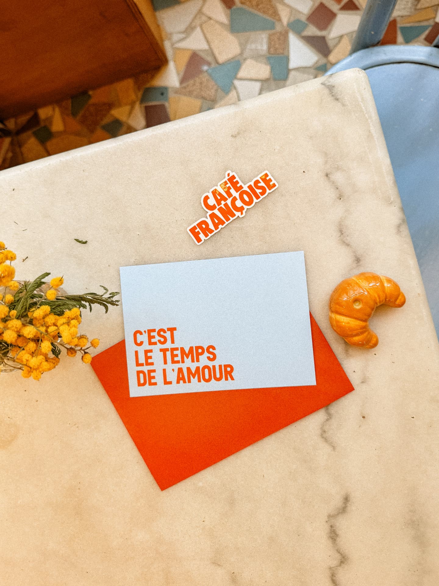 Carte cadeau Café Françoise « C'est le temps de l'amour » posée sur une table en marbre